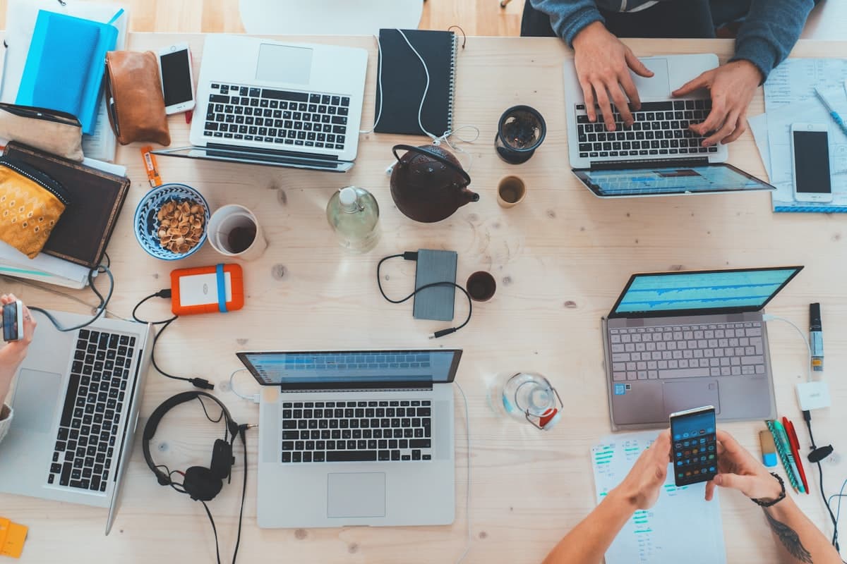 Collaborative workspace with laptops and devices on a desk, representing technology integration.