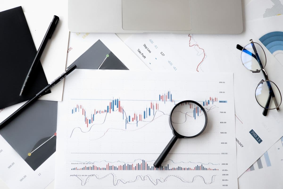 Desk with printed data charts, magnifying glass, glasses, and laptop during a data quality audit.